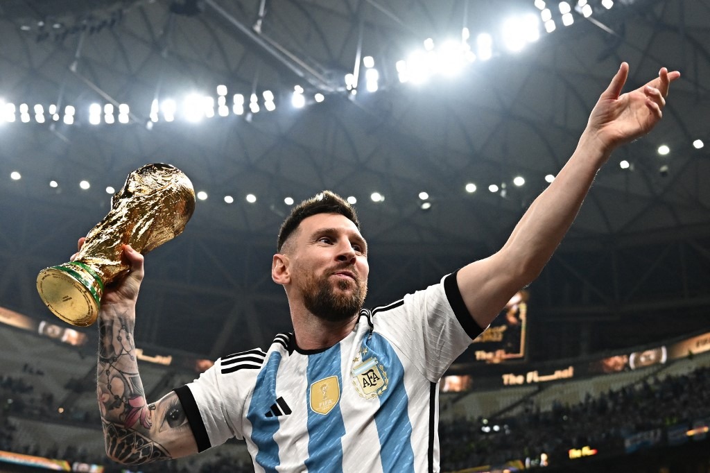 Lionel Messi sonríe con la Copa del Mundo en una mano y el otro brazo en alto, en el estadio de Lusail